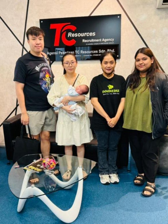 A young couple holding their newborn baby alongside their helper and two TC Resources staff